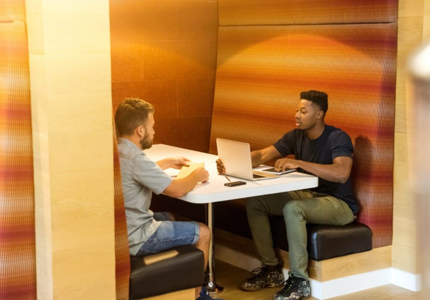Photo by LinkedIn Sales Navigator man sitting on black leather bench holding gray laptop computer on top of white wooden table