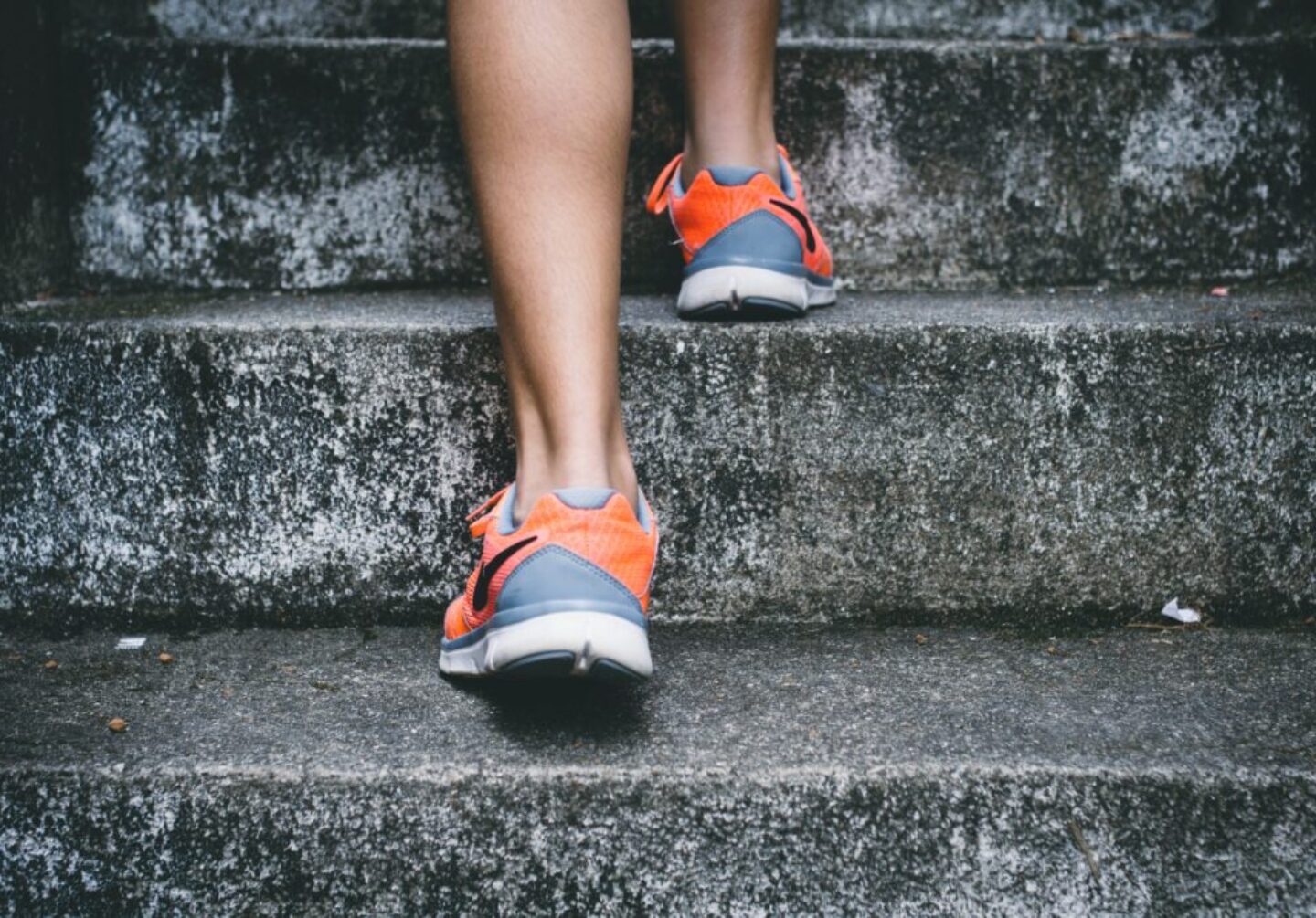 Photo by Bruno Nascimento person wearing orange and gray Nike shoes walking on gray concrete stairs