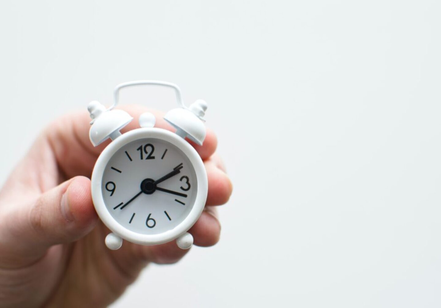person holding white mini bell alarmclock